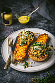 Mustard Glazed Butternut Squash Halves Stuffed with Farro and Kale on Plate with glaze in bowl, side angle