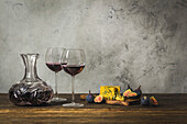 Rotwein in zwei Stielgläsern und Kristallkaraffe mit Blauschimmelkäse und Feigen