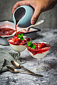 Yogurt and roasted Strawberry Parfaits in vintage glassware with syrup poured from a pale blue pitcher