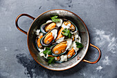 Muscheln Muscheln in Kupfer Kochpfanne mit Blauschimmelkäse-Sauce auf konkreten Hintergrund