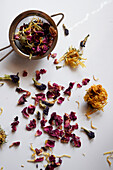Gemischter Kräutertee mit Rosenblüten, Ringelblumen, Lavendel und blauen Schmetterlingsblütlern im Teesieb, Nahaufnahme