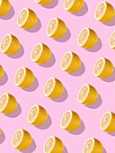 Full frame background with juicy lemon halves set against a bright pink background