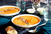 Red lentil piquillo pepper bisque in white bowls with blue napkins