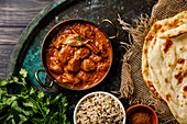 Chicken Tikka Masala spicy curry meat dish with rice and naan bread on a dark background