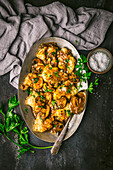 Chicken with Marsala and mushroom sauce on a metal plate with spoon and parsley
