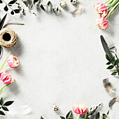 Easter background with spring flowers and cutlery on light grey background top view flat lay copy space square composition