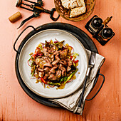 Salad with roast beef and vegetables on a pink background