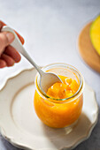 Lady lifts a spoonful of mango compote