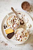 Two mugs of Irish cream mocha latte with whipped cream, grated chocolate and marshmallows