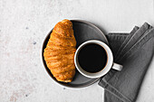 Cup of coffee and croissant over table