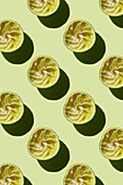 Vertikales Muster einer ausgepressten Limettenfrucht nach der Zubereitung eines frischen Getränks auf grünem Hintergrund Flatlay Food