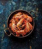 Boiled pink Greenland Prawn Shrimp in copper pan on blue background