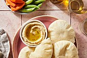 Flatbread and hummus on a pink tile