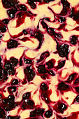 A close-up of the top of a baked cheesecake with blackcurrant ripple.