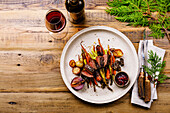 Grilled venison steak with baked vegetables, berry sauce and red wine on a wooden background