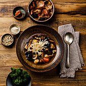 Healing Soup with roots, mushrooms and barley on wooden table background