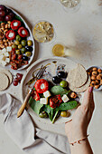 Antipasti platter in hand with oat cake and white wine