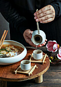 Japanese sake composition with Asian soup with rice noodles, Asian meal ceremony with magnolia flowers