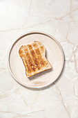 Toast on a ceramic plate in front of a marble background