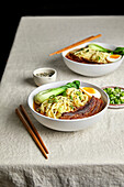 Ramen pork belly, bok choy and egg against a light-coloured neutral background