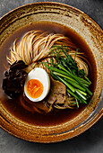 Ramen, Asian noodles in broth with beef tongue, mushrooms and eggs in a bowl