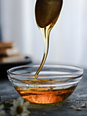 Honigtropfen in einer Glasschale mit Löffel