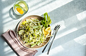 Healthy celery salad with apples and seeds in the bowl on a concrete background, seen from above