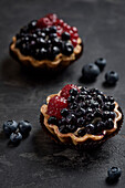 Pastries basket with blueberries and raspberries. Cake on a dark background.