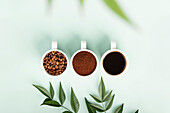 Ästhetische Darstellung von Kaffee in Bohnen, gemahlen und in flüssiger Form mit Grünzeug
