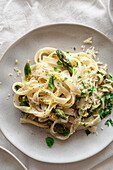 Lemony pasta with asparagus, vegan cheese and fresh basil on a spring-like, airy table
