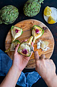 A woman scoops off the stem of an artichoke slice with a spoon