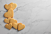 Ausgeschnittene Kekse in Herzform auf marmoriertem Hintergrund