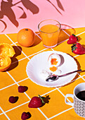 High angle of tasty breakfast of boiled egg surrounded with strawberries and raspberries with orange juice and cup of hot drink in morning