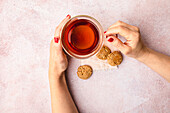 Cup of black tea with women's hands and homemade oat and walnut biscuits