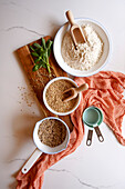 Buckwheat groats and flour ingredients cooking and baking concept on a white marble background. Top down flatlay