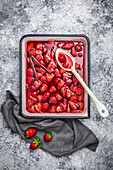 Roasted strawberries in an enameled tray with vanila pod