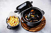 Shellfish Mussels Clams in black cooking dish pan and French Fries