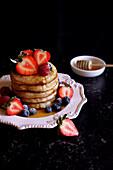 Stack of English crumpets with berries and honey
