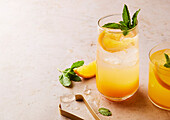 Orange-coloured sparkling cocktail with mint garnish