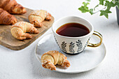 The cup of tea on a saucer and croissant