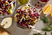 Radicchio salad with pears, pecans, pomegranate, pecans and basil vinaigrette on neutral brown background with green cloth