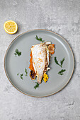 Freshly baked market fish served with fresh vegetables on a grey plate