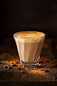 A heatproof glass holding a sweet latte drink topped with ground cinnamon.