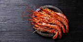 Raw fresh Prawn on metal plate on black burned wooden background copy space