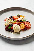Burrata, heirloom tomatoes, balsamic caviar, cherry puree, olive and cornichon base