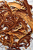 Melted chocolate and peanut butter swirled together on a marble surface.