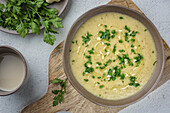 White vegetable cream soup. The dish is seasoned with parsley and garlic. Top view.