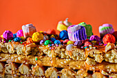 Cross sectional view of Peruvian nougat with glaze and colorful sprinkles placed over orange background