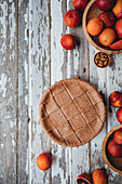 Top view of appetizing whole sweet blood orange pie placed on wooden table near citrus fruits and almonds