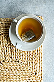 From above of white stylish cup of hot aromatic Green tea with tag placed on with on concrete table